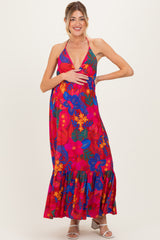 woman wearing a vibrant floral maternity maxi dress with a halter neckline and a visible baby bump
