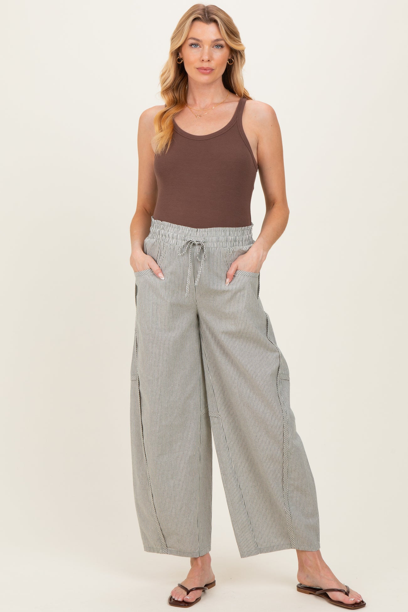 woman wearing a brown maternity tank top and striped wide-leg pants with pockets