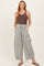 woman wearing a brown maternity tank top and striped wide-leg pants with pockets