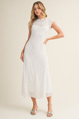 woman wearing a white short sleeve midi dress with textured pattern and a flowy skirt
