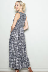 woman wearing a navy blue floral maxi dress with tiered layers, turned slightly to the side