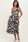 woman wearing a black and white patterned maternity dress with pockets and spaghetti straps, smiling at the camera