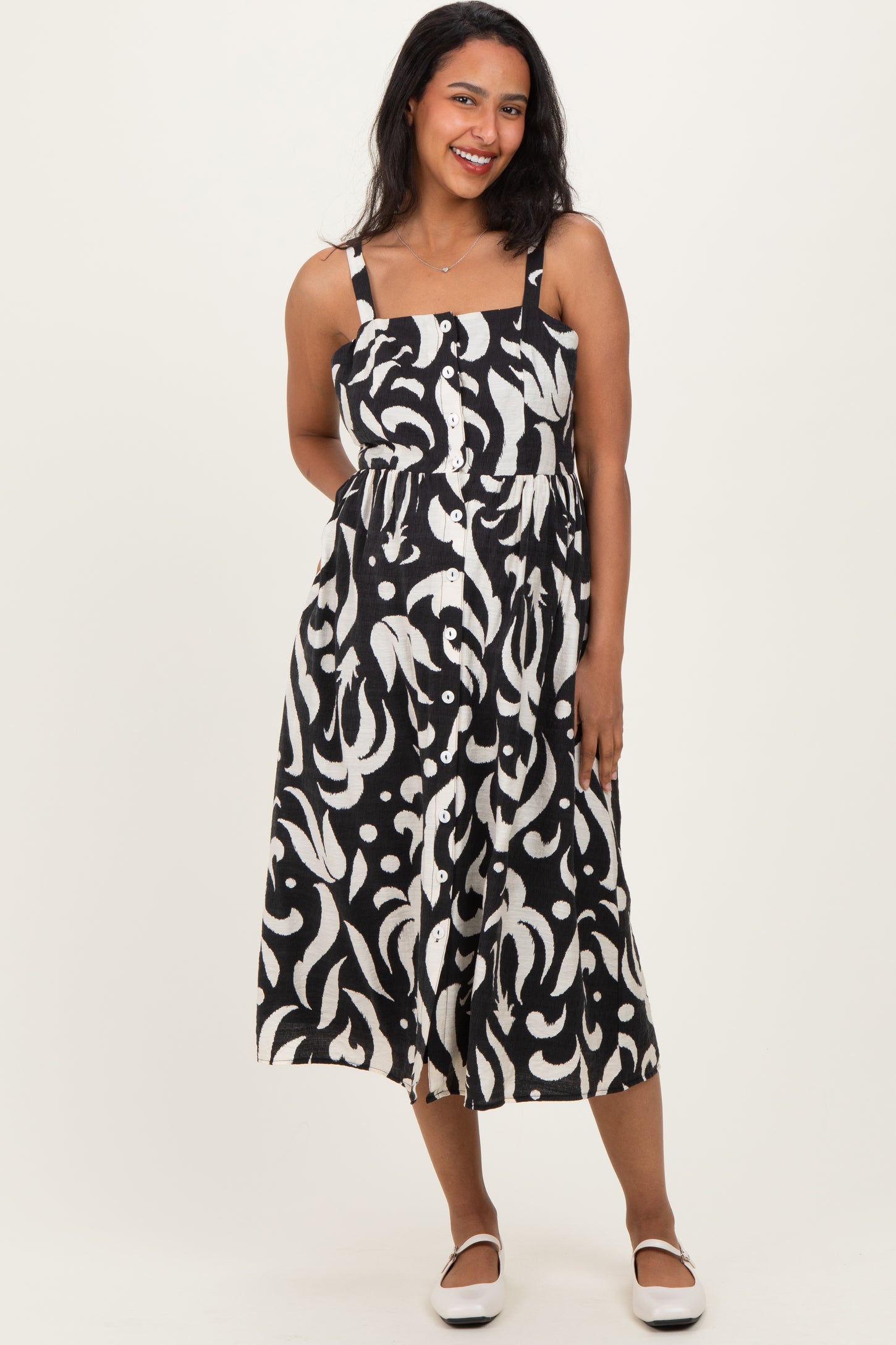 woman wearing a black and white patterned maternity dress with spaghetti straps and a button-up front