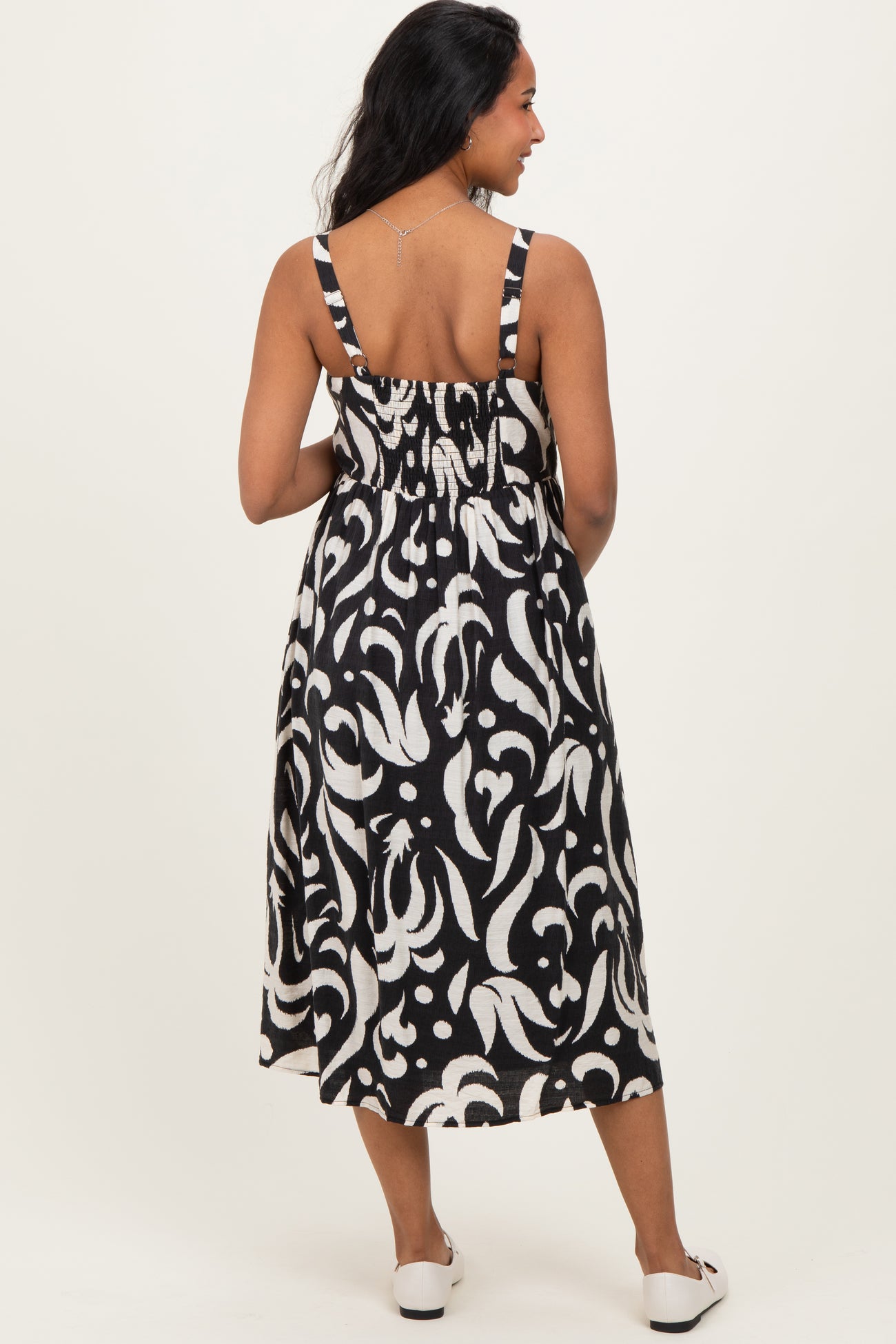 woman wearing a black and white patterned maternity dress with smocked back and spaghetti straps, showing a baby bump
