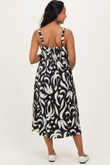 woman wearing a black and white patterned maternity dress with smocked back and spaghetti straps, showing a baby bump