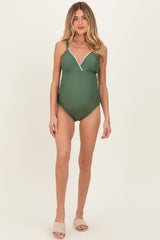 woman wearing a dark green maternity swimsuit with a v-neckline and decorative trim, showcasing her baby bump