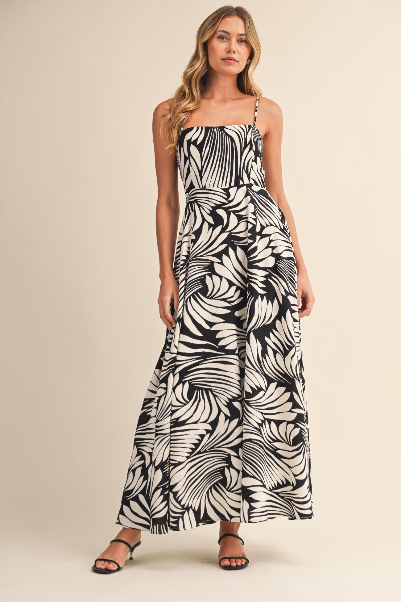 woman wearing a black and white floral print maxi dress with a fitted bodice and spaghetti straps