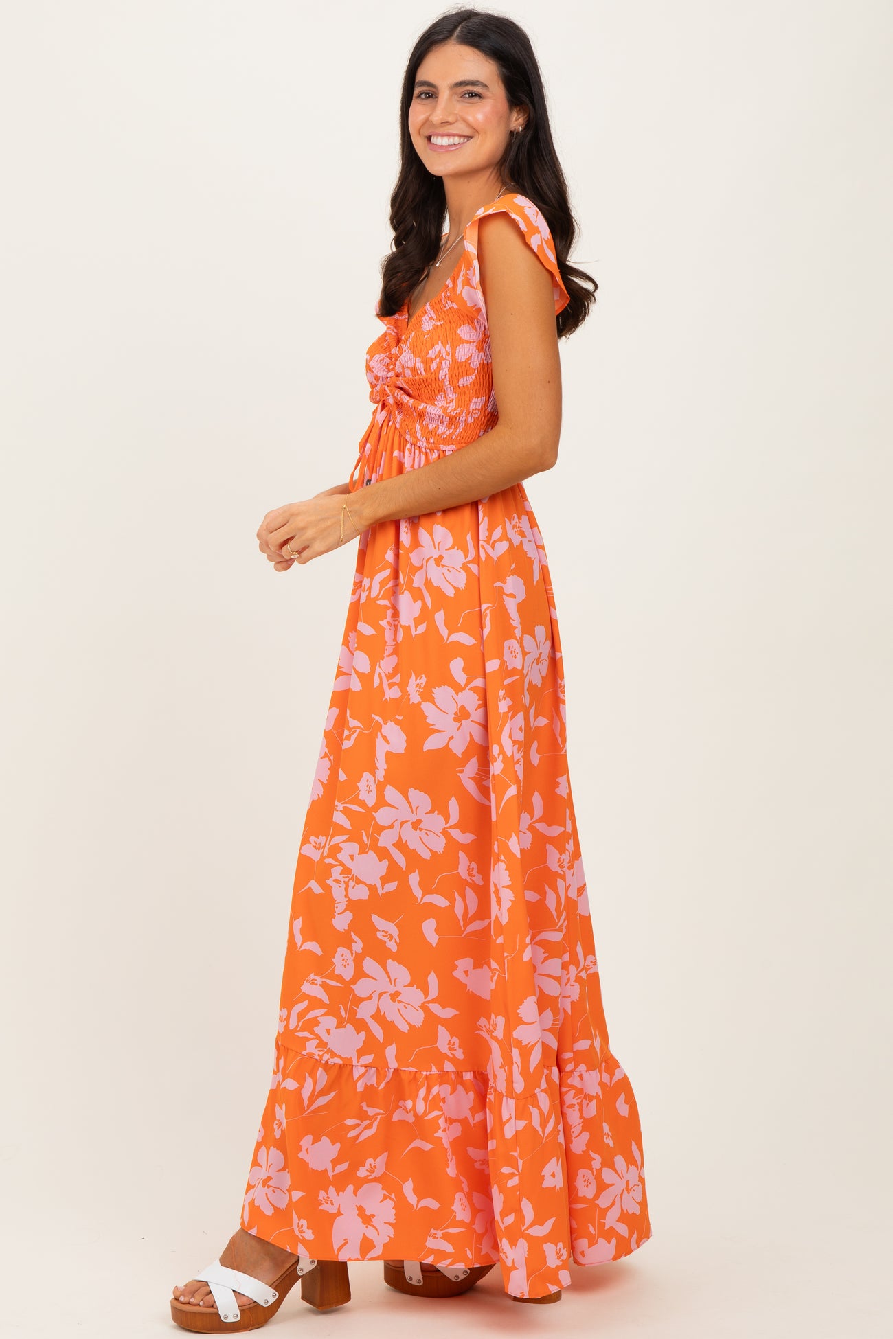 woman wearing an orange floral maxi dress with ruffled sleeves and a fitted bodice