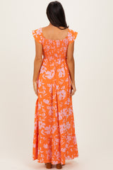 woman wearing an orange floral maxi dress with ruffled sleeves and a smocked bodice, seen from the back