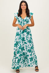 woman wearing a long floral maxi dress with cap sleeves and a cinched waist in shades of teal and white