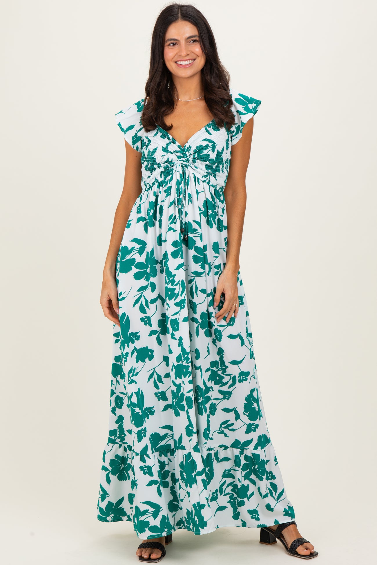 woman wearing a teal and white floral maxi dress with cap sleeves and a cinched bustline