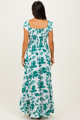 woman wearing a green and white floral print maxi dress with a smocked bodice and flutter sleeves, shown from the back