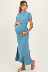 woman wearing a light blue short sleeve maternity dress and holding her baby bump