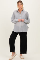 woman wearing a striped maternity button-up shirt and black wide-leg pants, showing her baby bump
