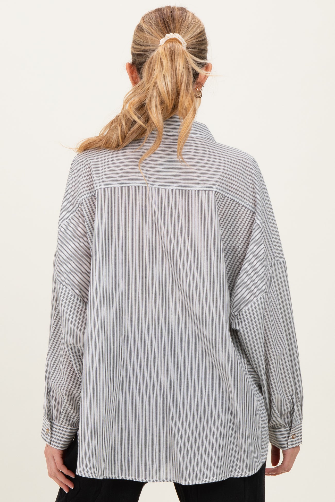 woman wearing a striped maternity shirt featuring a relaxed fit and long sleeves, shown from the back