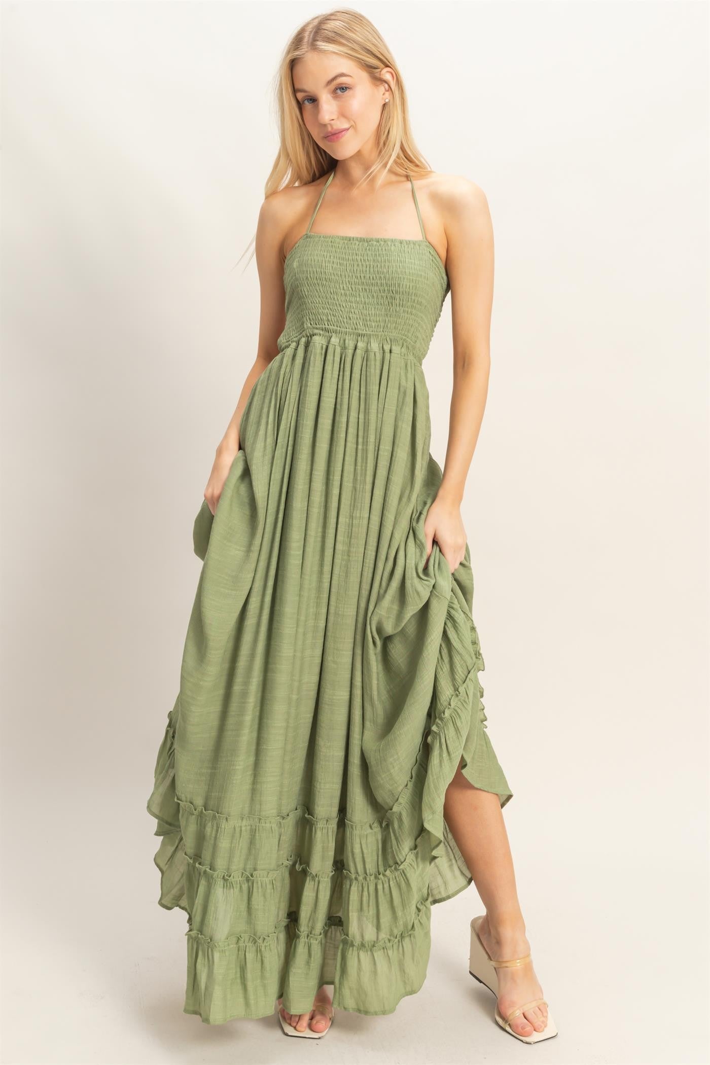 woman wearing a green smocked maxi dress with ruffle hem and side pockets