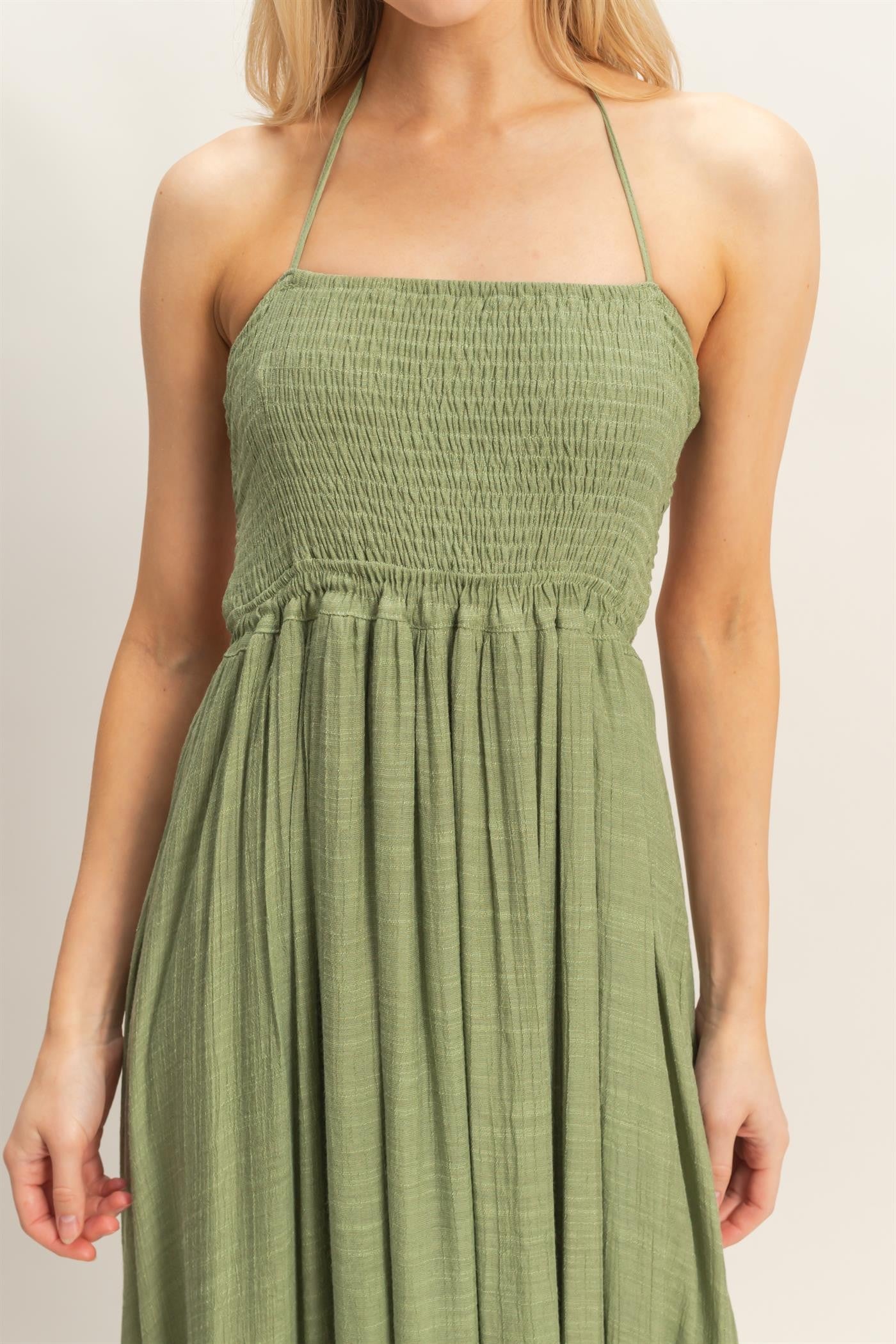woman wearing a green smocked maxi dress with a halter neck and a flowing skirt