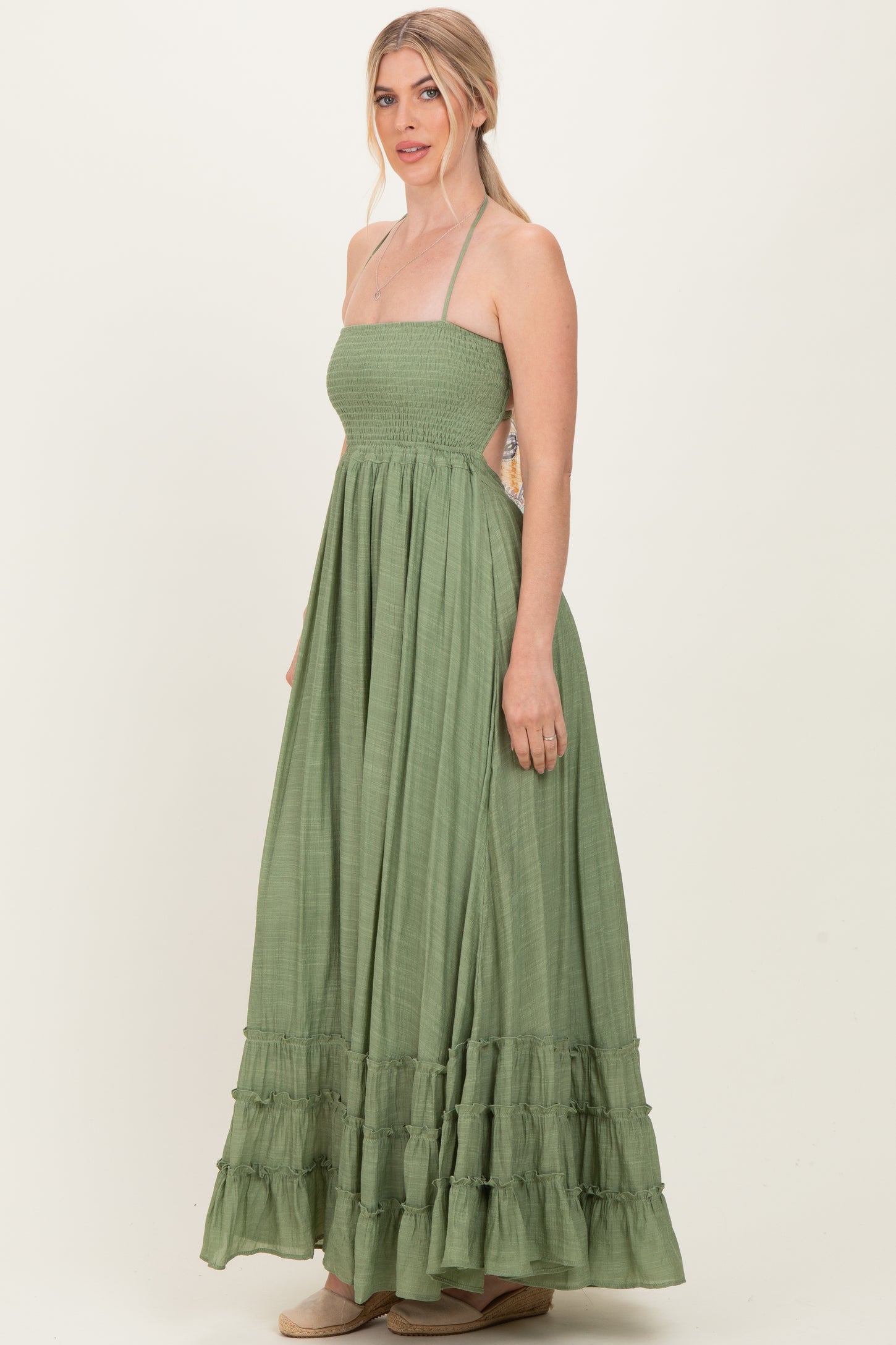 woman wearing a sage green maxi dress with a smocked bodice and ruffle hemline