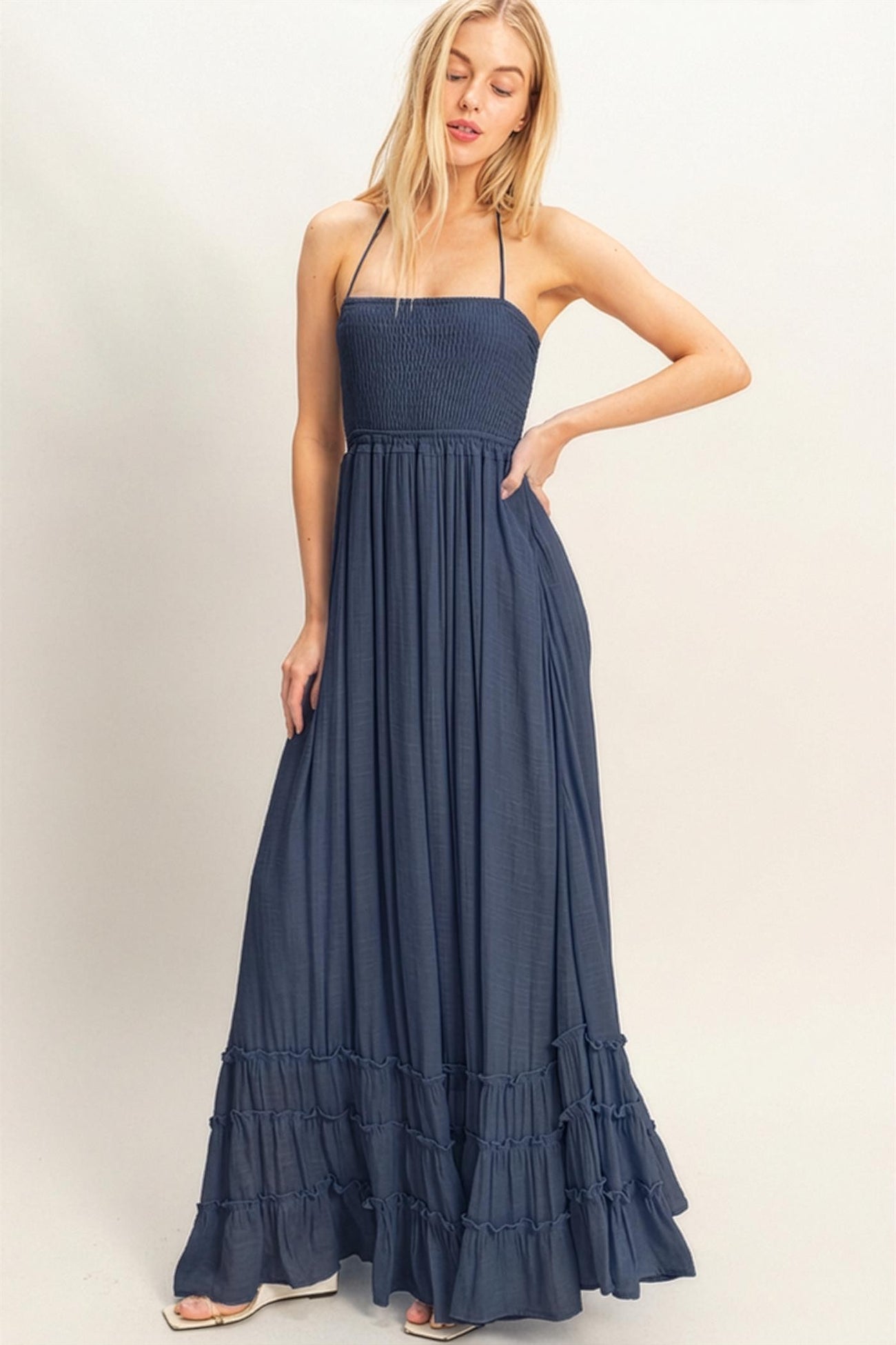 woman wearing a navy blue smocked maxi dress with ruffle hem and thin straps