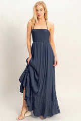 woman wearing a navy blue strapless maxi dress with a smocked bodice and ruffled hemline