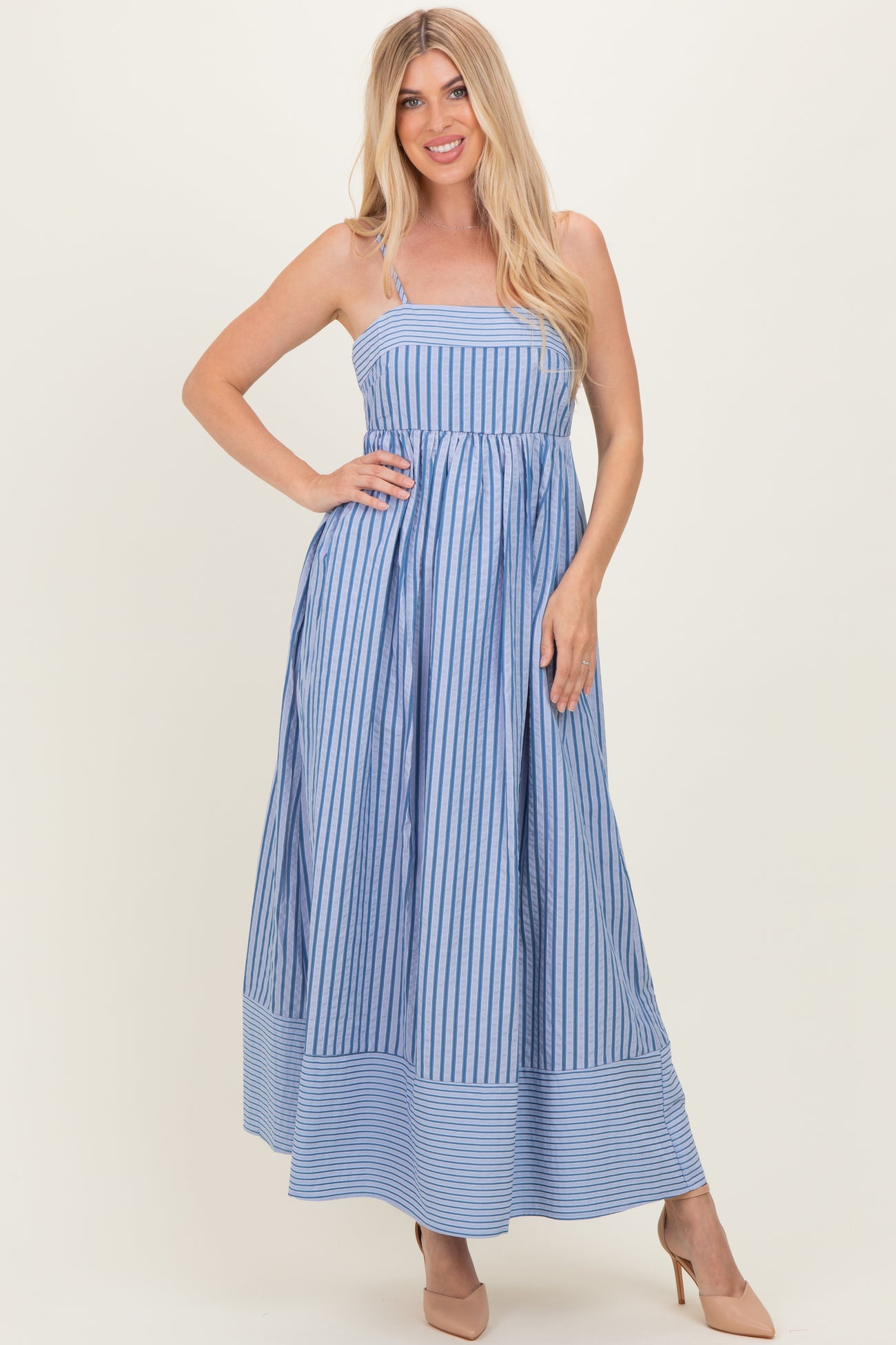 woman wearing a blue and white striped maxi dress with spaghetti straps and a flared skirt