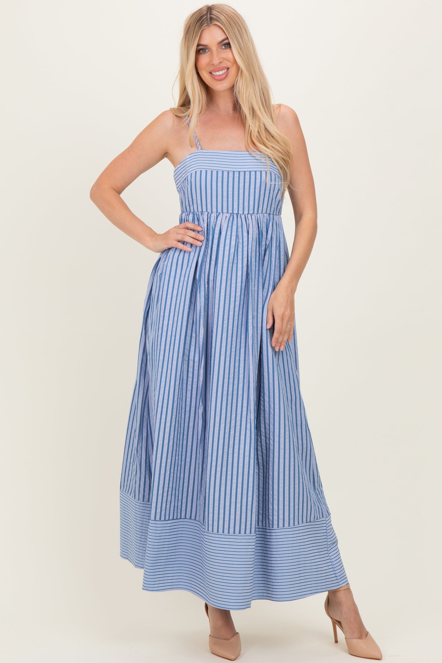 woman wearing a blue and white striped maxi dress with spaghetti straps and a flared skirt