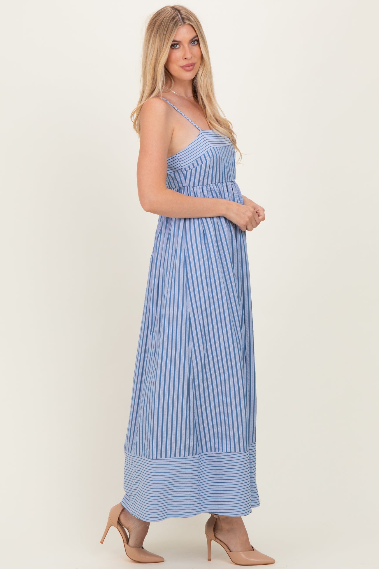 woman wearing a blue and white striped maxi dress with spaghetti straps and a flowy silhouette