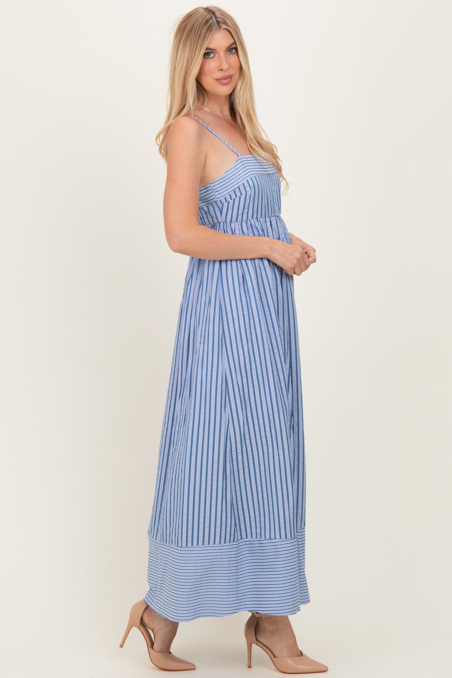 woman wearing a blue and white striped maxi dress with spaghetti straps and a flowy silhouette