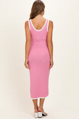 woman wearing a pink knitted maternity dress with white trim, shown from the back