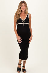 woman wearing a black maternity dress with white trim and a tie neckline, showing her baby bump