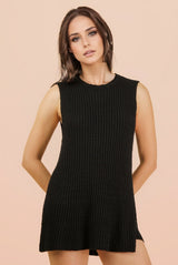 woman wearing a sleeveless black ribbed knit sweater dress with a relaxed fit