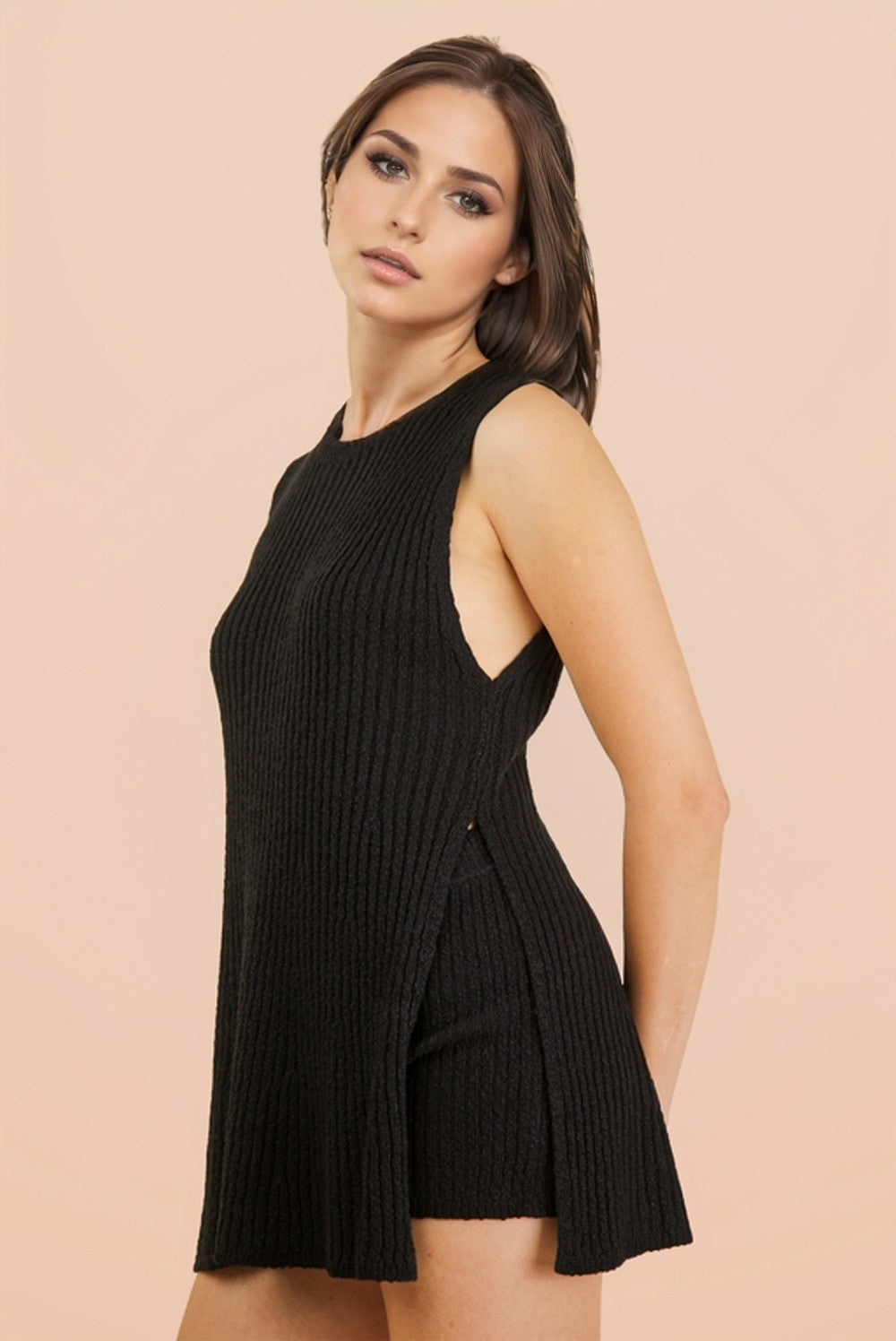 woman wearing a black ribbed knit sleeveless tunic top with side slits