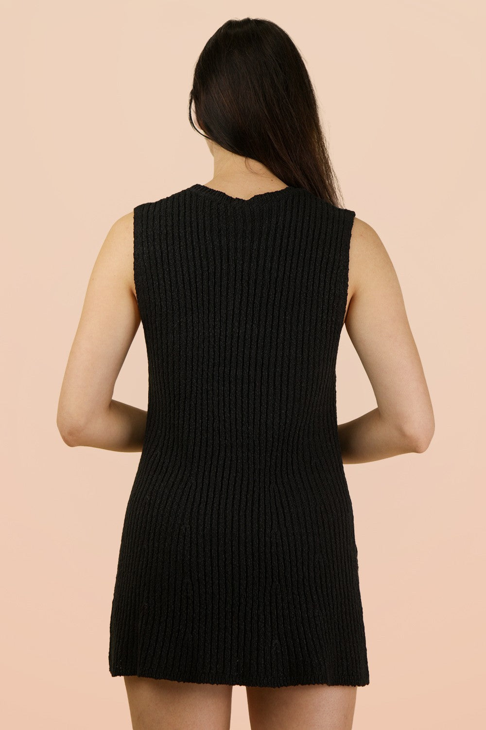 woman wearing a sleeveless black ribbed knit dress, seen from the back