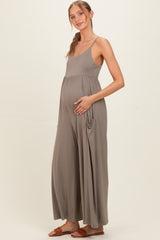 woman wearing a taupe maternity jumpsuit with a fitted bodice and loose wide legs, showing her baby bump