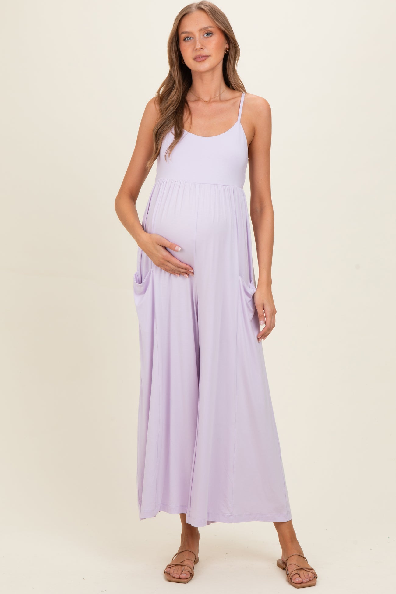 woman wearing a lavender maternity maxi dress with pockets and holding her baby bump