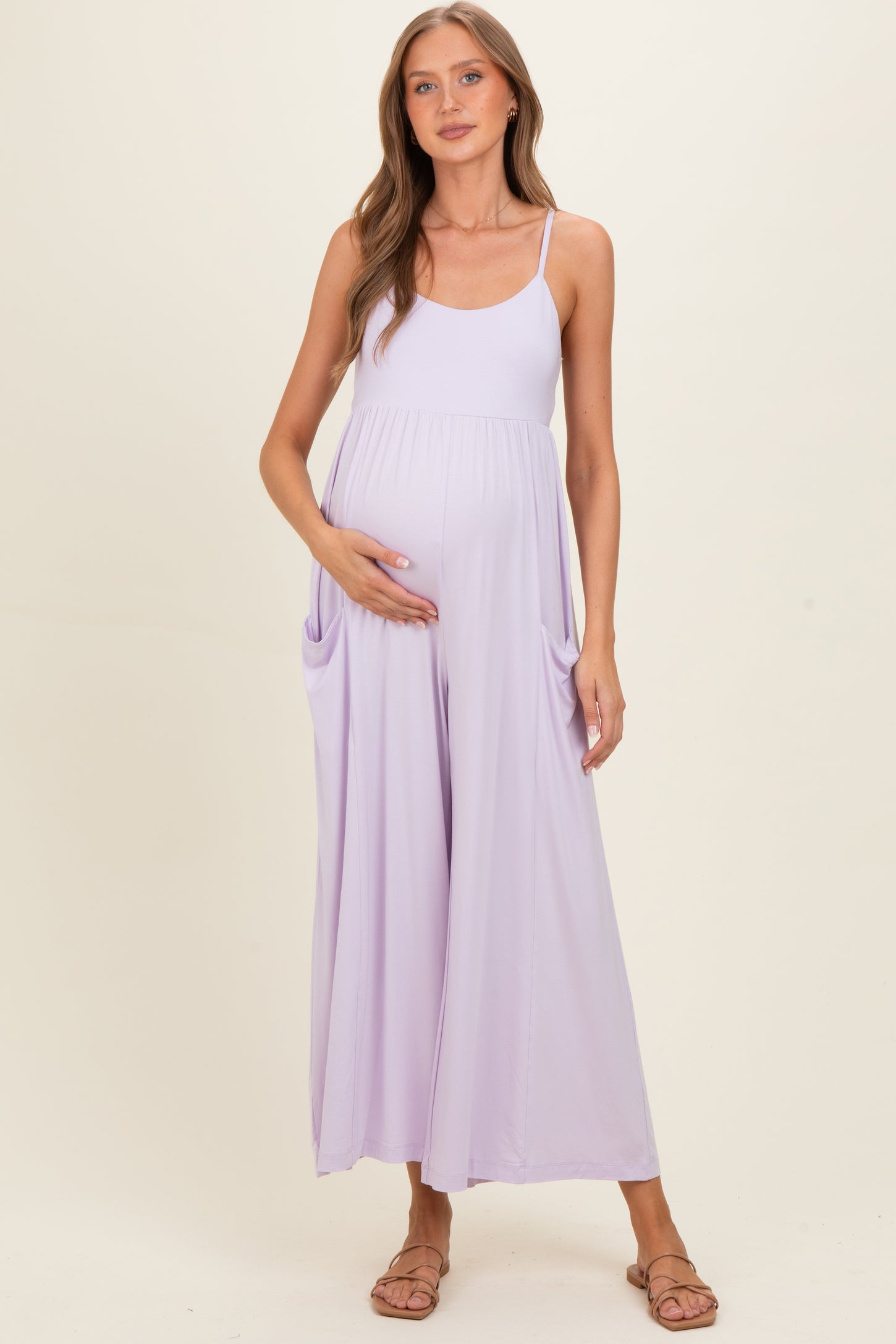 woman wearing a lavender maternity maxi dress with pockets and holding her baby bump