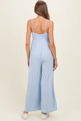woman wearing a light blue maternity jumpsuit with wide legs and adjustable straps, seen from the back