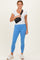 woman wearing a white fitted short sleeve top and blue leggings, holding a black crossbody bag
