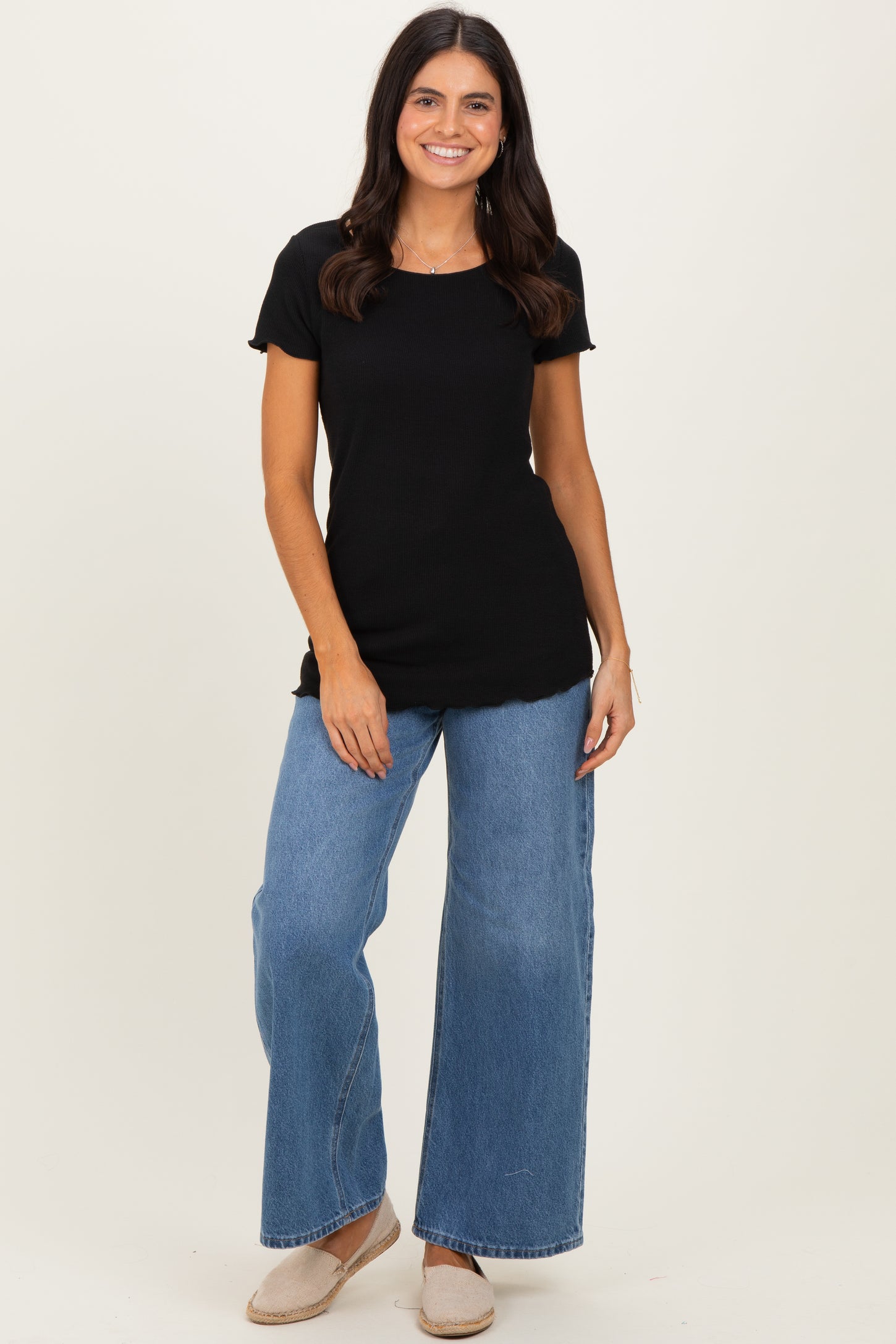 woman wearing a black ribbed short sleeve top and high-waisted wide leg blue jeans