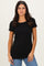 woman wearing a black short sleeve ribbed top with a scoop neckline and subtle scalloped hem, paired with blue jeans