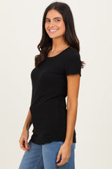 woman wearing a black short sleeve ribbed top with a relaxed fit and frayed hem, styled with denim jeans