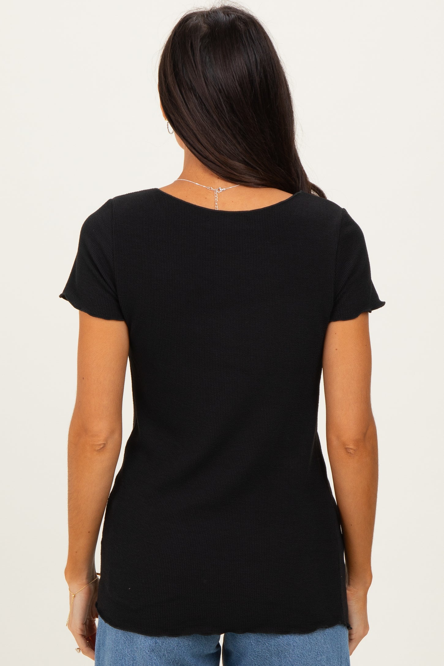 woman wearing a black short sleeve top viewed from the back with a scoop neckline and a relaxed fit