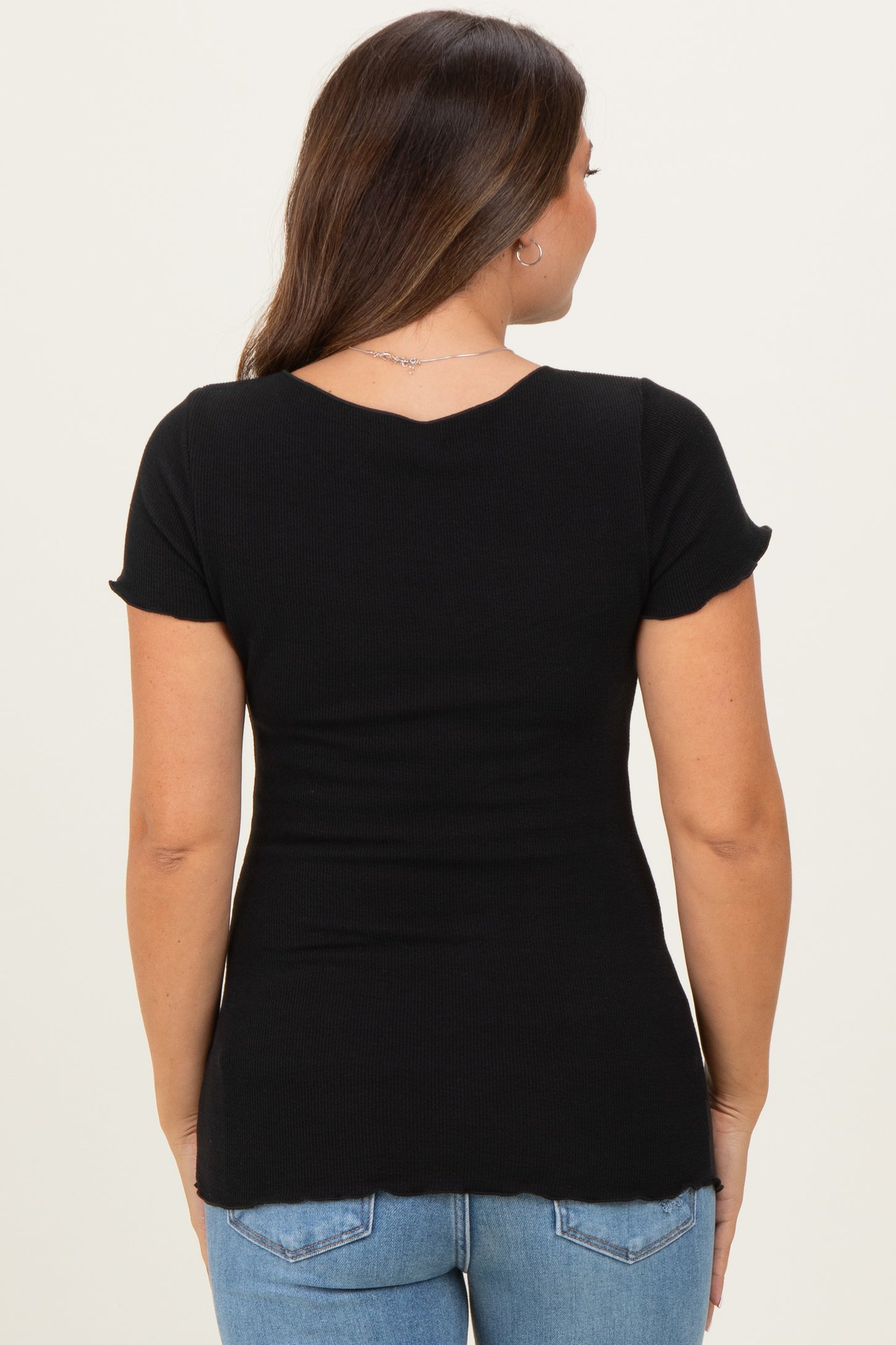 woman wearing a black short sleeve maternity top with a fitted silhouette and back scoop neckline