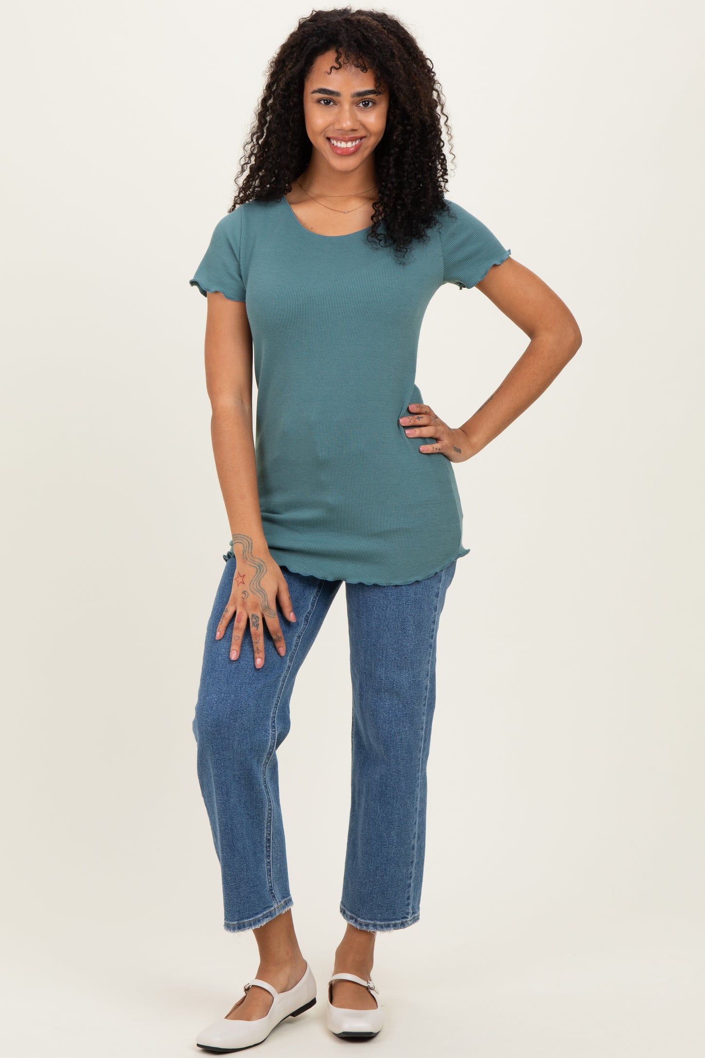 woman wearing a teal short sleeve ribbed top and blue high-waisted straight leg jeans with white slip-on shoes