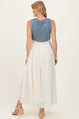 woman wearing a blue knitted maternity dress with a white skirt, showing a flowing design and back view