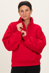 woman wearing a red half-zip pullover sweatshirt with balloon sleeves and a relaxed fit
