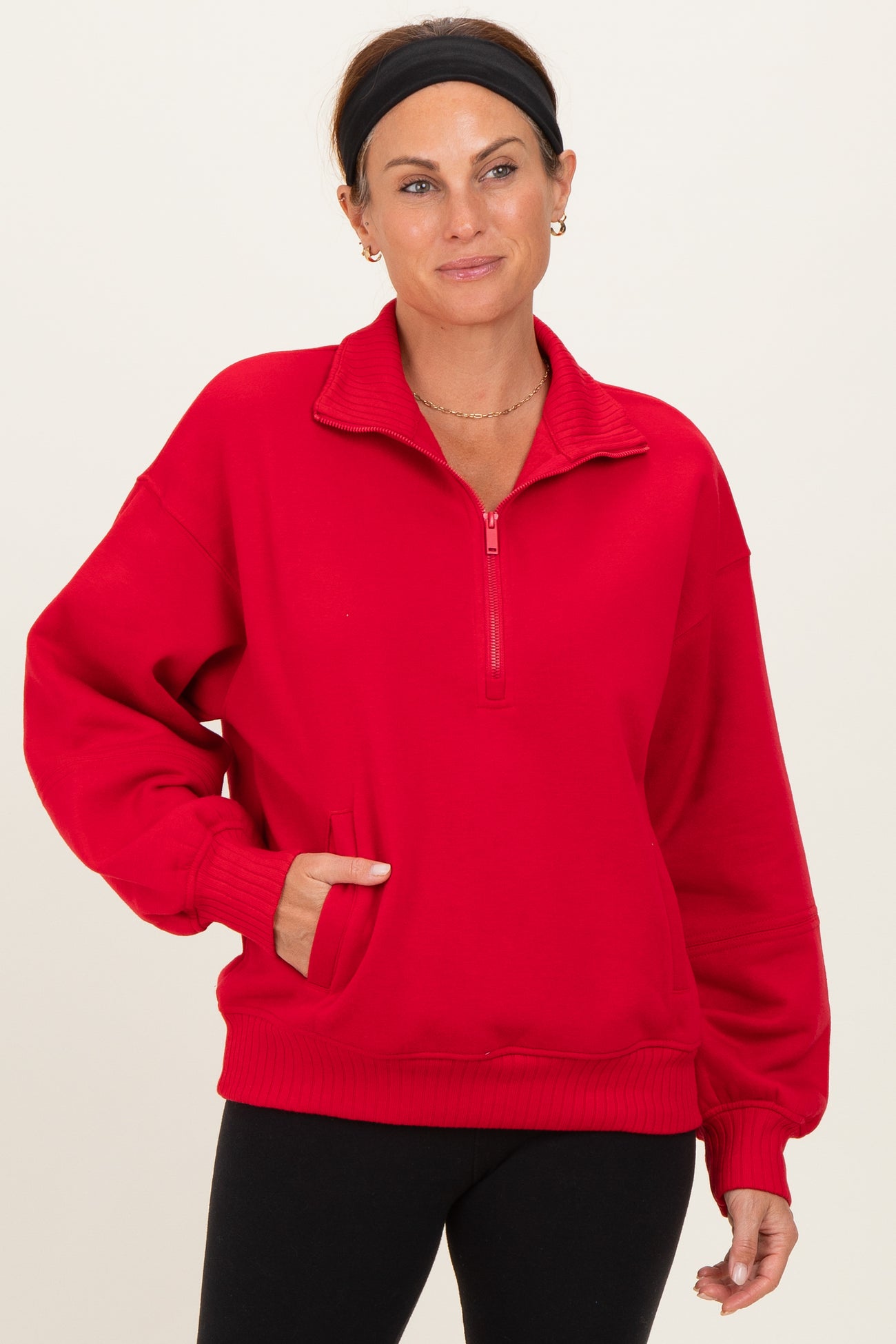 woman wearing a red quarter-zip sweatshirt with side pockets and a relaxed fit