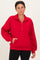woman wearing a red quarter-zip sweatshirt with side pockets and a relaxed fit