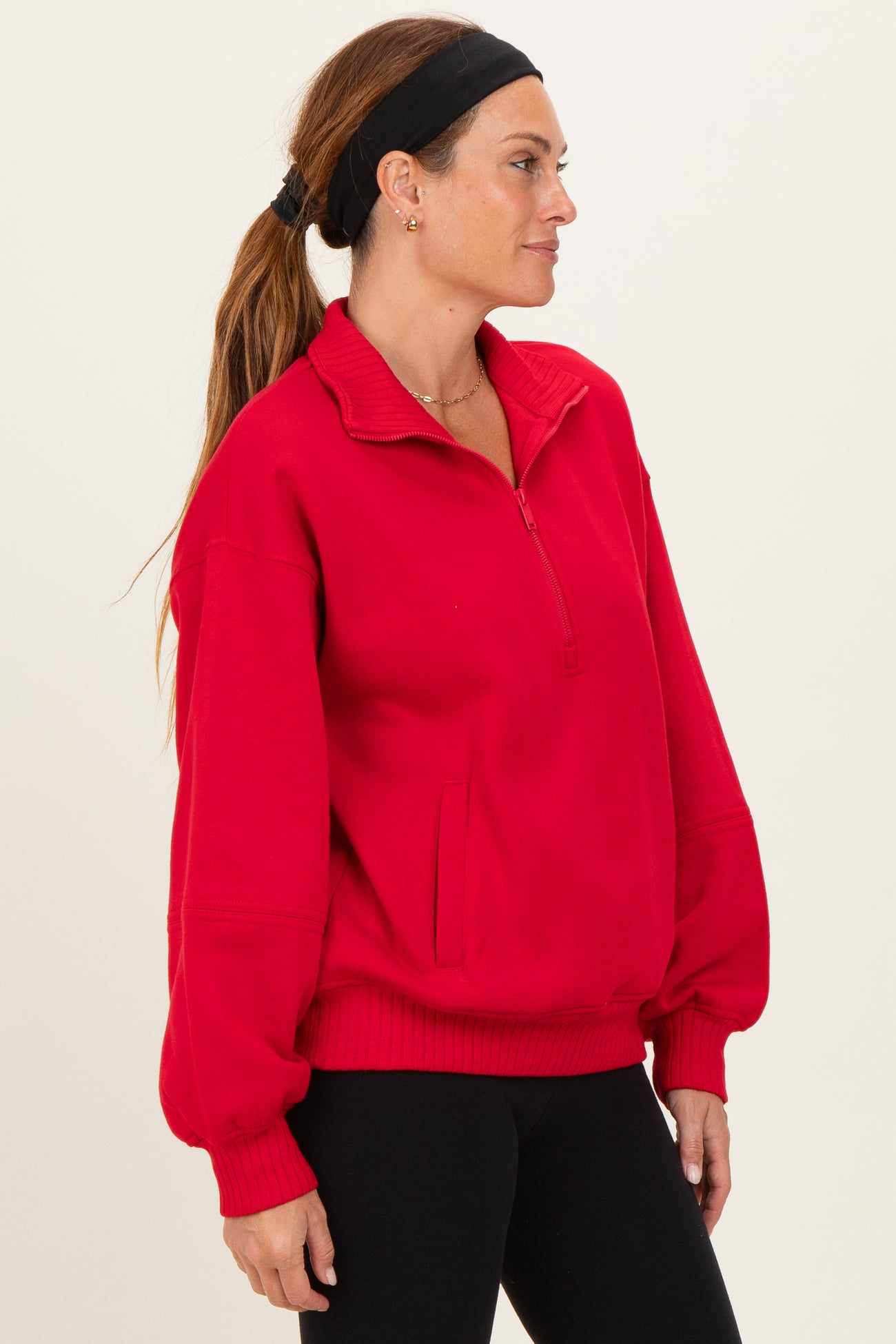 woman wearing a bright red quarter-zip pullover sweatshirt with a relaxed fit and side pockets