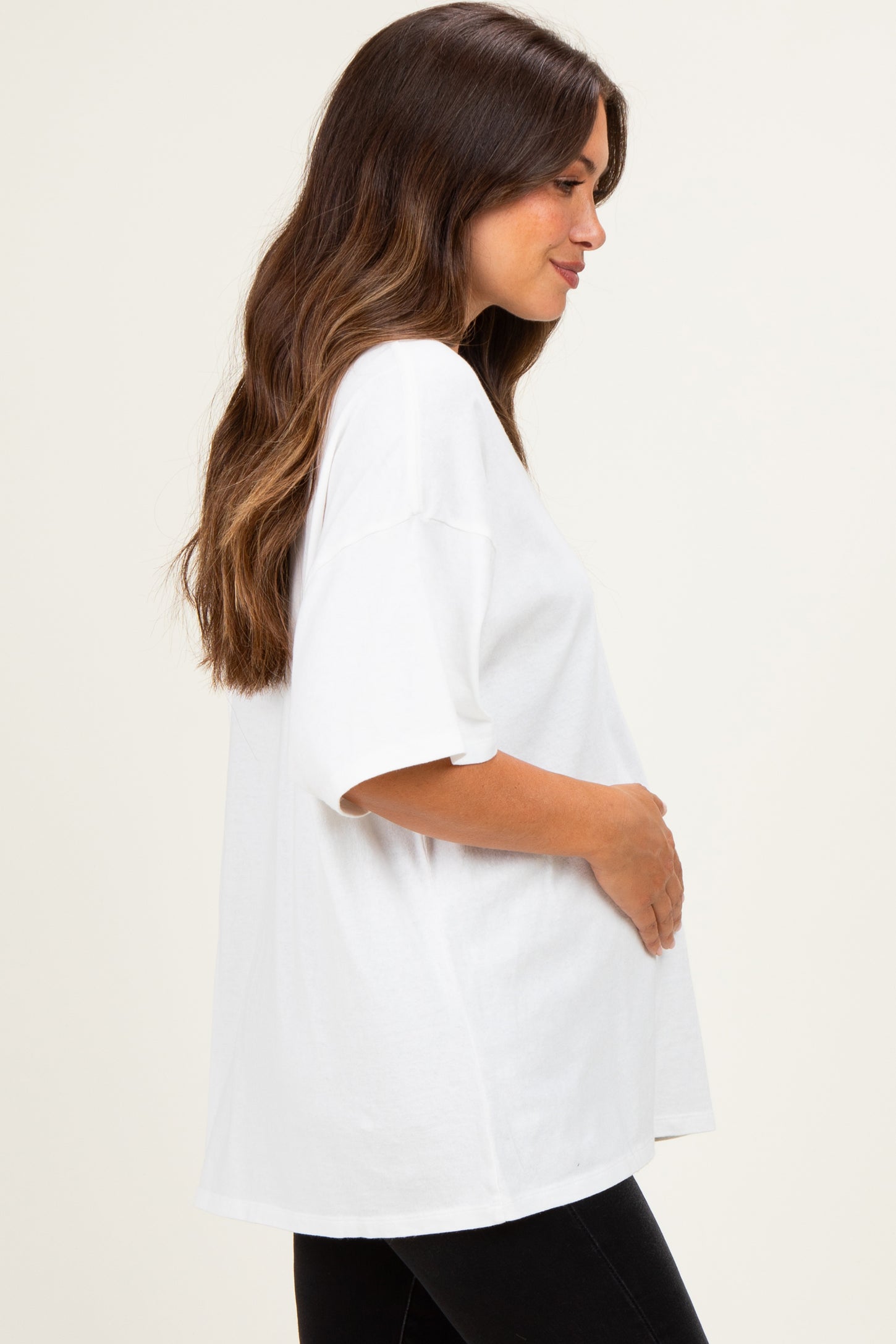 woman wearing a white oversized maternity t-shirt and holding her baby bump